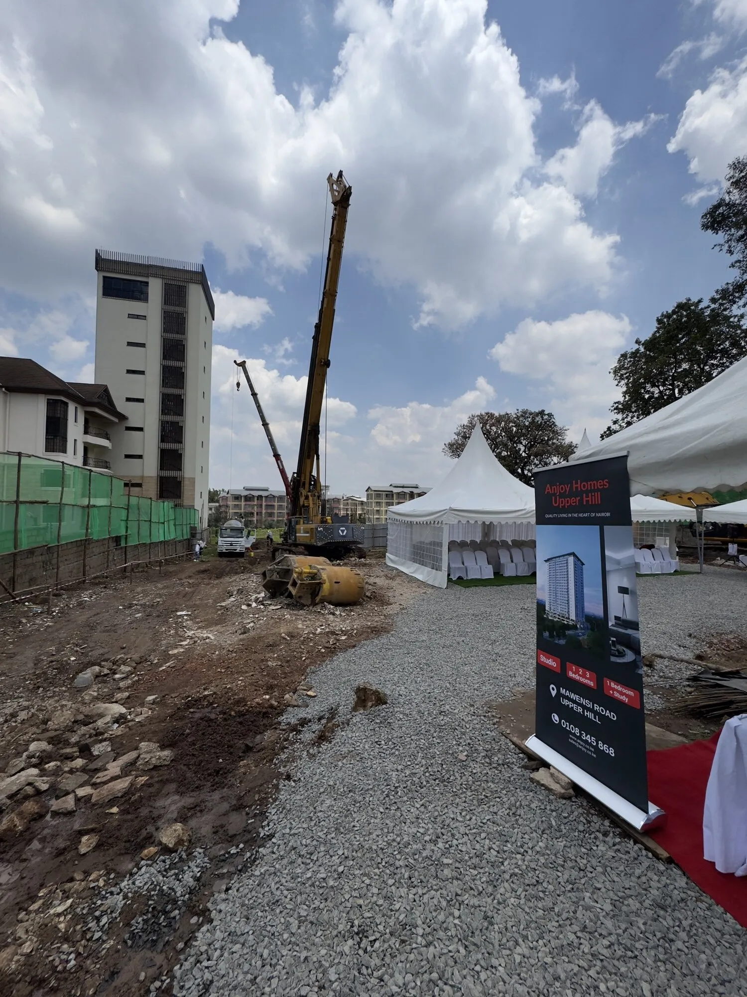 Ground-breaking on the cleared site, with a piling rig, a marquee and a project banner