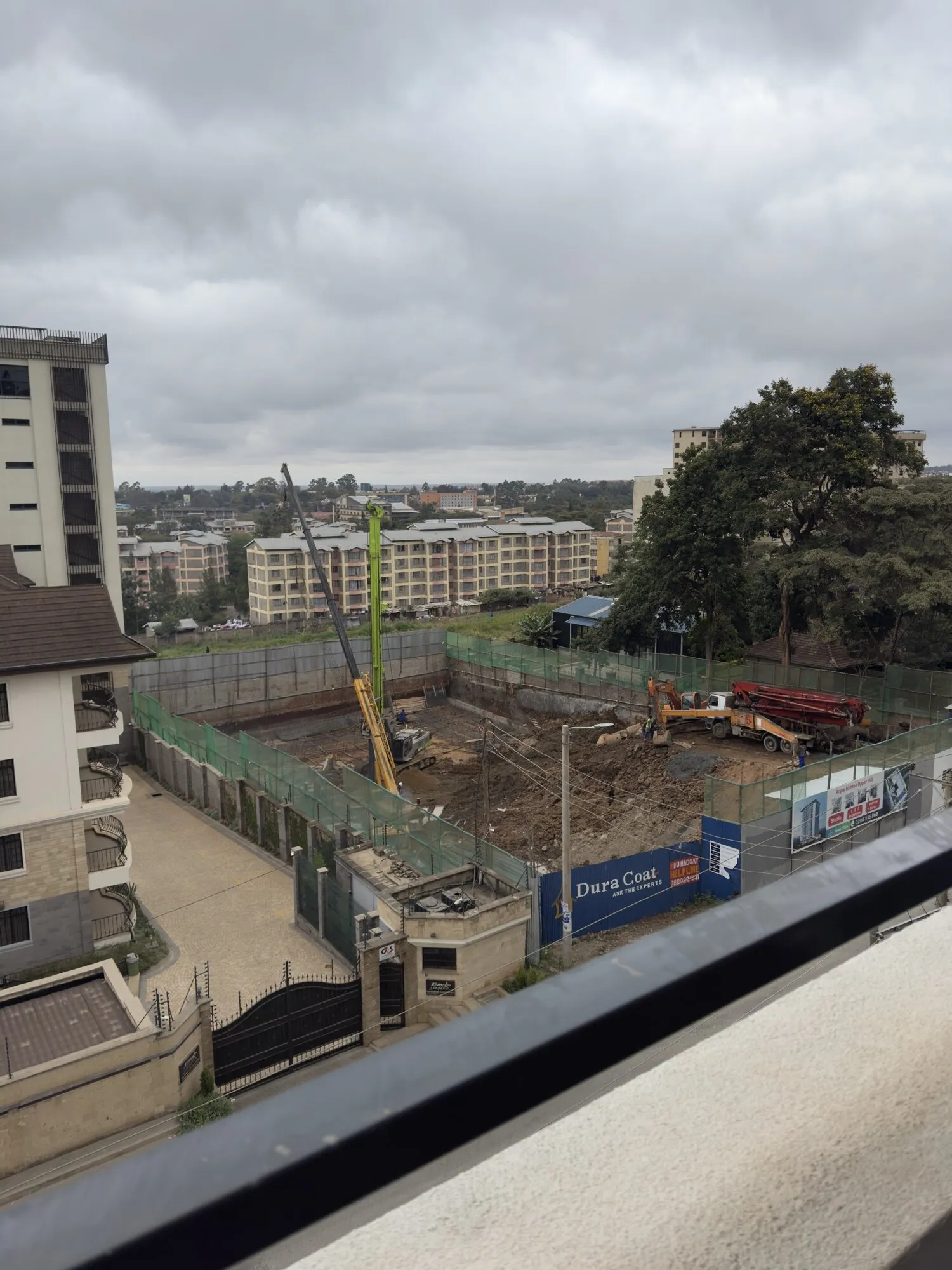 The excavated site seen from a neighbouring building, with diggers and a piling rig at work